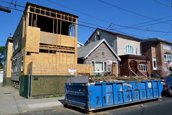 a garbage dumpster in front of a house being rebuilt